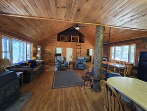 Interior d'una cabana amb terres de fusta, zona de menjador i saló amb sofà i seients.