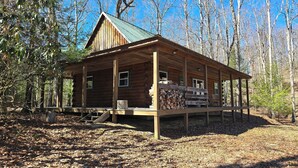 Eine rustikale Holzhütte mit Veranda und einem Holzstoß davor.