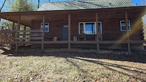 Eine Holzhütte mit Veranda, Tür und Fenstern.