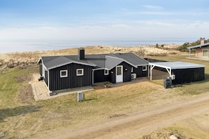 A modern house with a large garage, a covered patio, and a view of the beach.