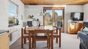A modern interior with a dining table, chairs, a sofa, a TV, and a wooden ceiling. - Cosy holiday home for 6 near beach/sea (Sydals)