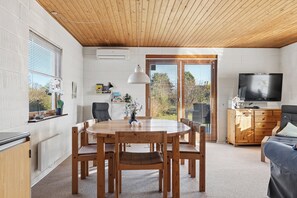 A modern interior with a dining table, chairs, a sofa, a TV, and a wooden ceiling. - Cosy holiday home for 6 near beachsea (Sydals)
