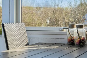 Ein Korbstuhl und ein Tisch mit zwei durchsichtigen Gläsern voller Erdbeeren.