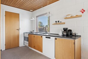 A compact kitchen with wooden cabinets, a built-in oven, and a dishwasher. - Cosy holiday home for 6 near beachsea (Sydals)