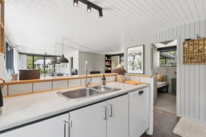 A modern kitchen with a large island, built-in appliances, and a view to the outdoors. - Lovely holiday home near the water (Hurup Thy)