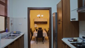 Una cocina funcional con armarios de madera, un refrigerador de acero inoxidable y un comedor con mesa y sillas.