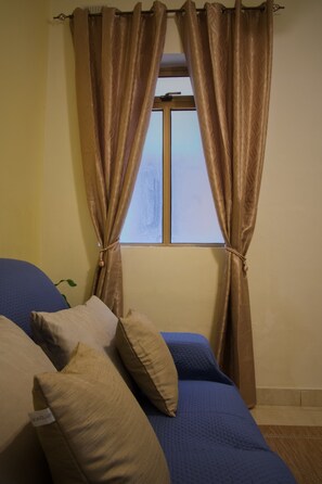 A room with a bed, beige pillows, and brown curtains tied at the top. - 2 bedroom Bormla flat - 2 minutes from Valletta Ferry Service! (Bormla)