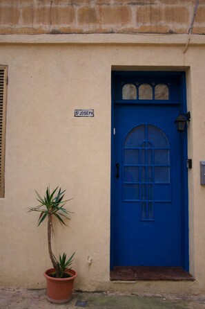 A building with a blue door, a sign reading "S Joseph," and a potted plant beside it. - 2 bedroom Bormla flat - 2 minutes from Valletta Ferry Service! (Bormla)
