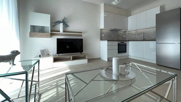 A modern kitchen with white cabinetry, a built-in oven, and a stainless steel refrigerator. - Athenean Modern Escape near Marina Flisvos-E1 (Paleo Faliro)