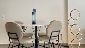 A dining area with a round table, four chairs, a tall vase, and a wall-mounted circular light fixture. - Athenean Modern Escape near Marina Flisvos-E1 (Paleo Faliro)