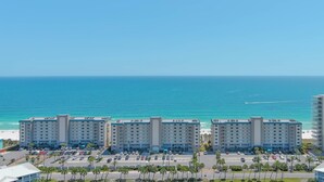 A hotel with multiple floors, a parking lot, and a view of the ocean. - Sandy Key 732 | Spacious Beachfront Condo | Pools, Hot Tub & Tennis | My Beach Getaways (Pensacola)