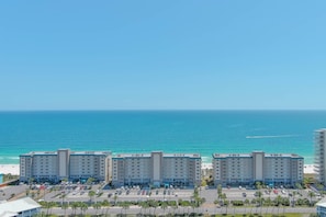 A hotel with multiple floors, a parking lot, and a view of the ocean. - Sandy Key 732 | Spacious Beachfront Condo | Pools, Hot Tub & Tennis | My Beach Getaways (Pensacola)