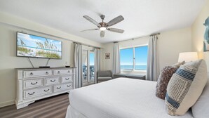 A hotel room with a bed, a ceiling fan, a television, a dresser, and a view of the ocean. - Sandy Key 732 | Spacious Beachfront Condo | Pools, Hot Tub & Tennis | My Beach Getaways (Pensacola)