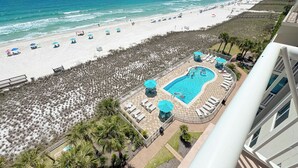 A beach view with a pool area, including lounge chairs and umbrellas. - Sandy Key 732 | Spacious Beachfront Condo | Pools, Hot Tub & Tennis | My Beach Getaways (Pensacola)