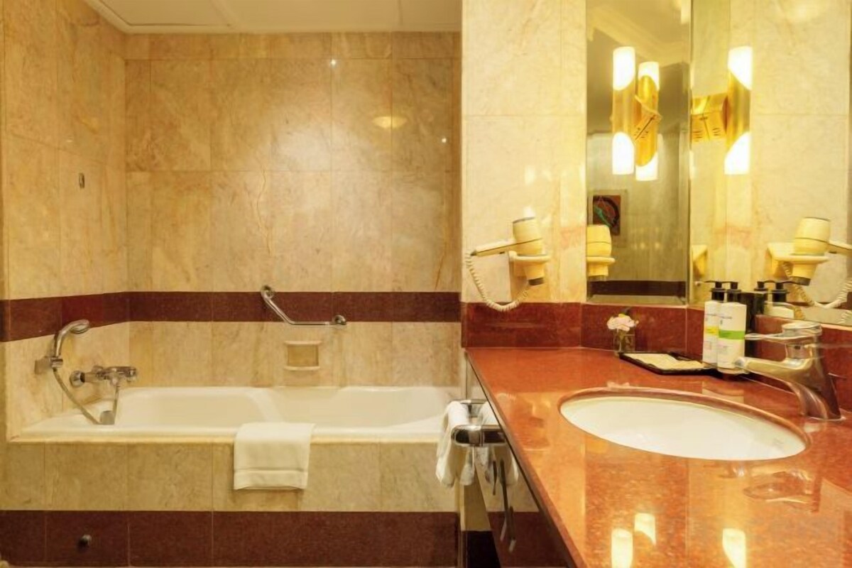 A bathroom with a bathtub, a sink, and a mirror.