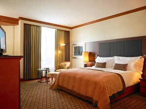 Une chambre d’hôtel avec un grand lit, un bureau, une chaise et un téléviseur.