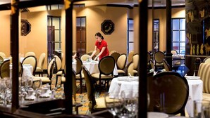 A restaurant with tables set for dining, a waiter attending to a table, and traditional decor. - The Heritage Grand Khon Kaen Hotel and Convention (Khon Kaen)