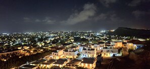 A nighttime view of a residential area with illuminated buildings and a hilly landscape in the background. - AnochíLuz - Modern 3-bedroom apartment near Mambo beach (Willemstad)