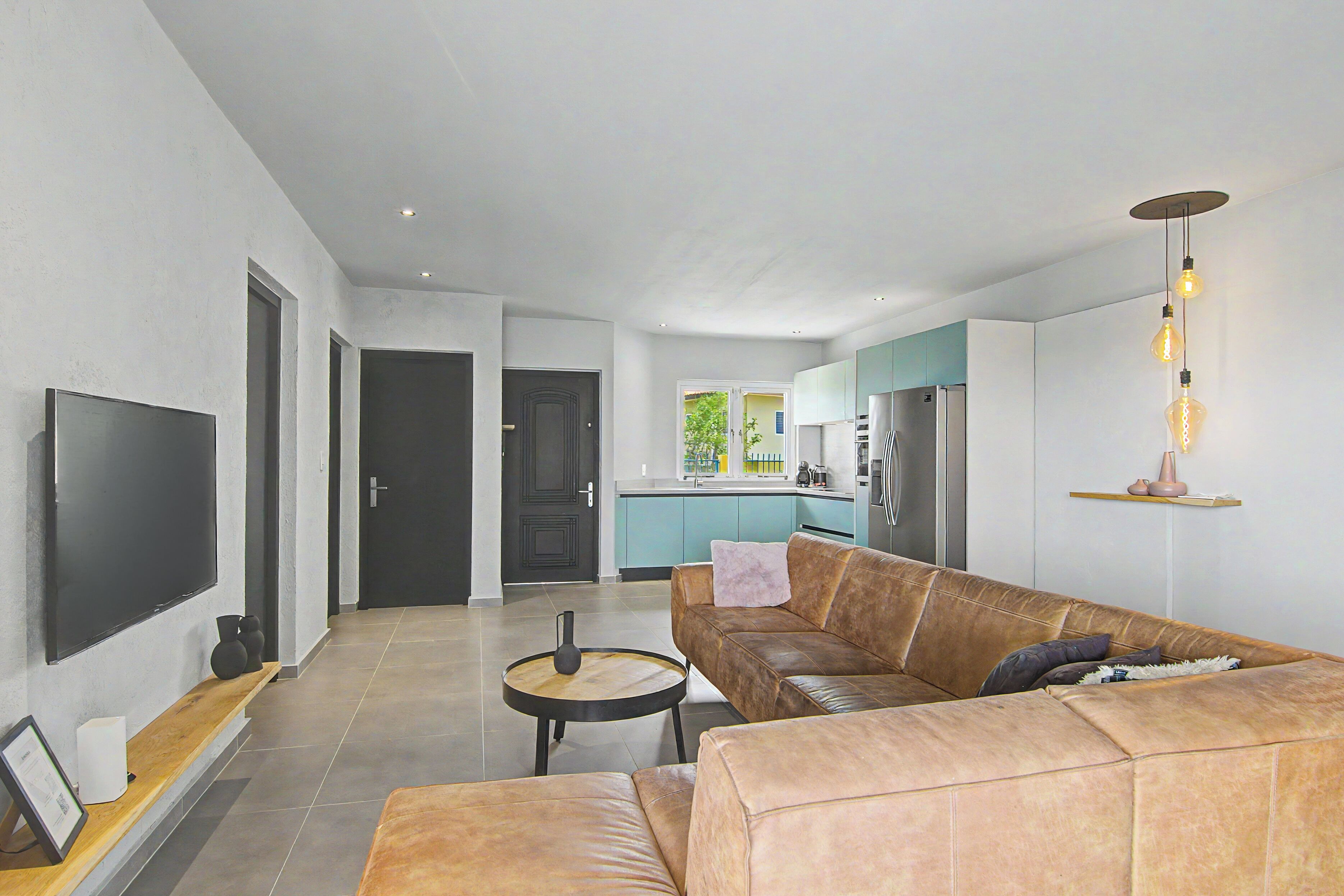 A modern living room with a leather sofa, a flat-screen TV, and a round coffee table.