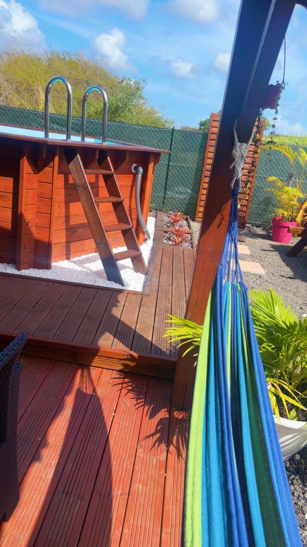 Une terrasse en bois avec un jacuzzi et un hamac.