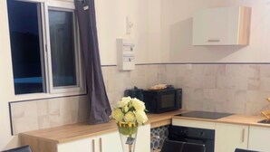 Une cuisine moderne avec une table à manger en verre, des chaises noires et un vase de fleurs.