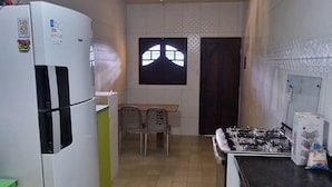 A kitchen with a refrigerator, stove, and a window with a decorative pattern.