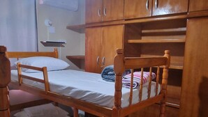 A room with a bunk bed, wooden cabinets, a ceiling fan, and a tiled floor.