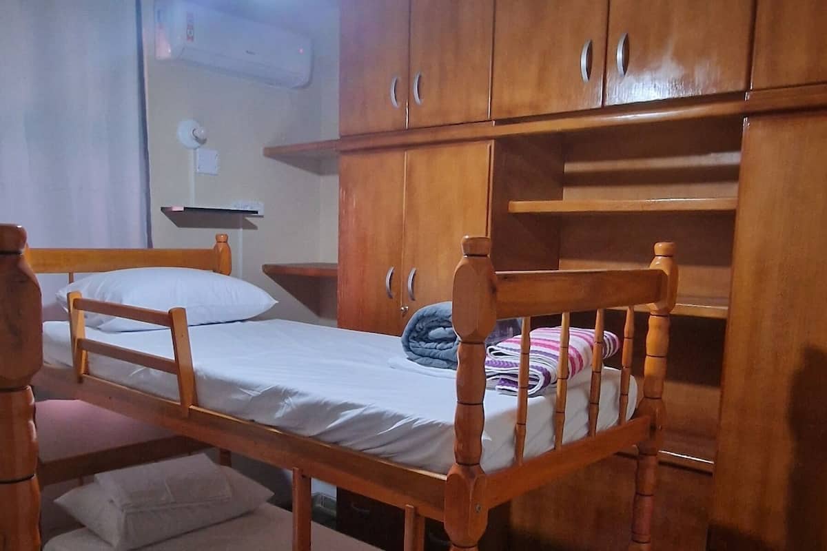 Una stanza con una cuccetta, armadietti in legno, una ventola a soffitto e un pavimento piastrellato.