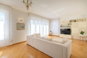 A modern living room with a sofa, TV, and a chandelier. - Vittoria Luxury Apartment (Treviso)