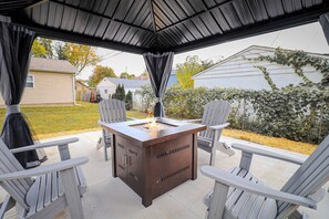 Une terrasse extérieure dotée d’un foyer en métal, entourée de fauteuils Adirondack.