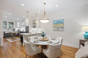 A modern kitchen with white cabinetry, a round dining table with white chairs, and a hanging light fixture. - UPDATED Seabook Townhome, Elevator, Golf Cart, Club Access at Fairway One Villas, SUMMER OPENINGS! (Seabrook Island)