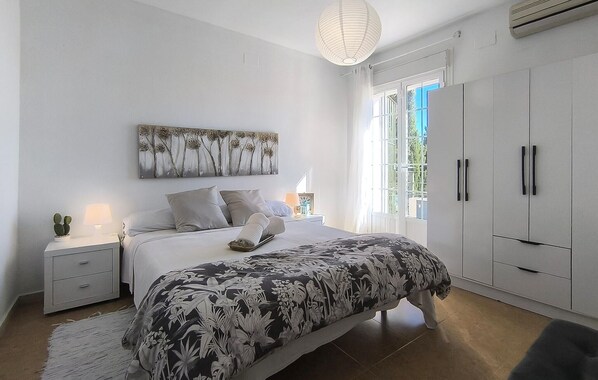 A bedroom with a bed, nightstands, a wall art piece, a wardrobe, and a window with curtains.