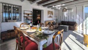 A dining area with a long table, red upholstered chairs, and a bottle of wine. - Cozy home in Guillena (Guillena)