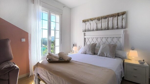 A bedroom with a bed, bedside tables, a nightstand, a window, and a chair. - Cozy home in Guillena (Guillena)