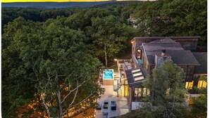 Una casa moderna con una terrazza, una vasca idromassaggio e vista sulla foresta circostante.