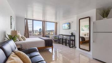 Een moderne hotelkamer met een bed, een sofa, een bureau en een groot raam met uitzicht op de stad.