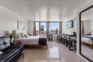 Une chambre d’hôtel moderne équipée d’un lit, d’un canapé, d’un coin repas et d’une grande fenêtre donnant sur la ville.