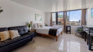 A modern bedroom with a bed, a black leather sofa, a small table, and a chair.