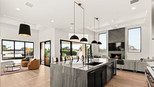 Cozinha moderna com ilha central, luminárias pendentes pretas e lareira.
