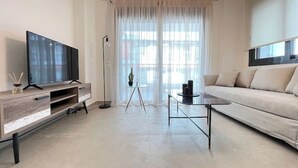 Un salon moderne avec un téléviseur, un canapé, une table basse et une lampe sur pied.