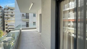 Un appartement moderne doté d’un balcon, de grandes fenêtres et offrant une vue sur d’autres immeubles.