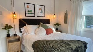 A neatly arranged bedroom with a bed, bedside tables, and wall art.