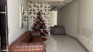 Uma sala de estar espaçosa com um sofá de couro marrom, um pinheiro de Natal branco e um moderno lustre.
