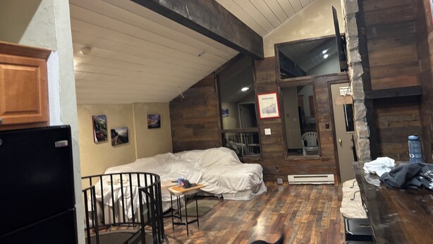 A rustic room with a wooden ceiling, a bed, a small table, and a refrigerator. - Cozy 2-bedroom condo with AC in pleasant Whitefish (Whitefish)