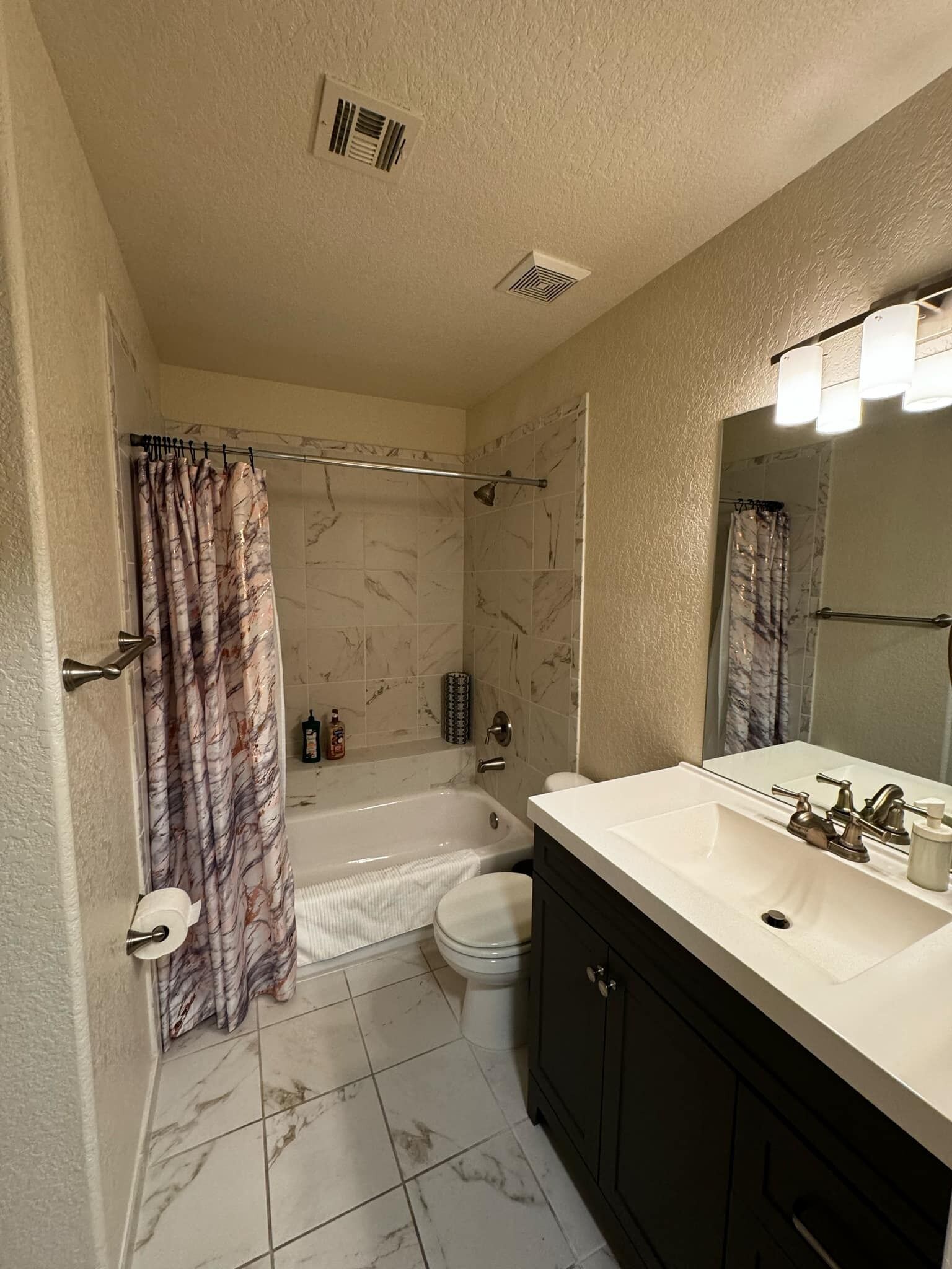 A bathroom with a bathtub, toilet, and vanity with a mirror.