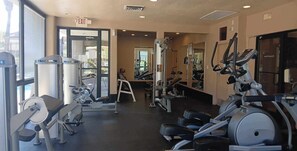 Een fitnessruimte met cardioapparatuur, gewichten en spiegels.