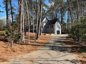 A two-story house with a steep driveway, surrounded by tall trees and a clear sky. - Spacious 5-bedroom Master's Retreat, North Augusta. 8.7 mi. to Augusta National (North Augusta)