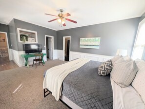 A bedroom with a bed, a desk, a television, a ceiling fan, and a painting on the wall. - Spacious 5-bedroom Master's Retreat, North Augusta. 8.7 mi. to Augusta National (North Augusta)