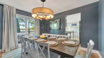 A dining area with a wooden table, white chairs, and a hanging light fixture.