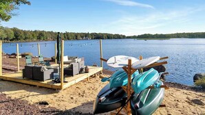 Järvenrantaterassi, jossa on kajakkeja, suppilautailulauta ja ulkotilaa istumiseen.